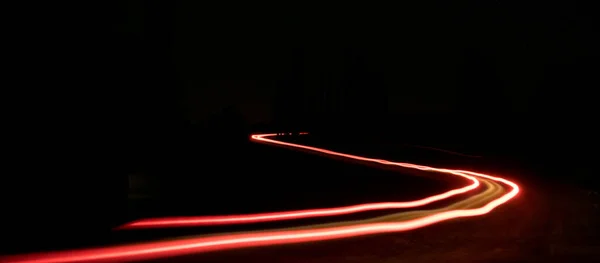 黒の夜に赤の湾曲した明るい光の歩道 車が速く動く — ストック写真