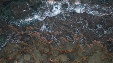 Sea waves crashing on roacky coast at sunset. Drone footage. Moving waves