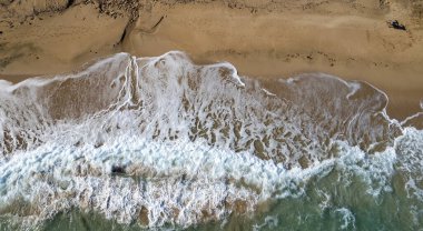 Aerial view of ocean waves breaking on a sandy beach. Nature background