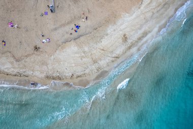 Drone aerial of people relaxing in a sandy beach in winter. Fog tree bay beach, holiday resort Protaras Cyprus.