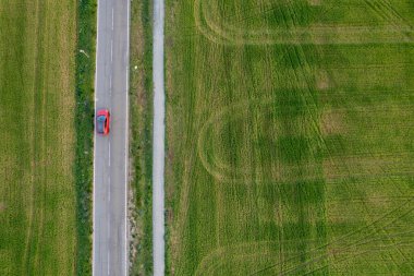 Kırmızı arabanın insansız hava aracı kırsal bir yolda ilerliyor. Yeşil tarım alanı olan bir kırsal bölge. Kıbrıs