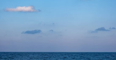 Gün batımında ufukta deniz suyu ve mavi gökyüzünün panoramik manzarası.