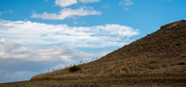 Mountain cliff wild terrain and blue cloudy sky. Nature background