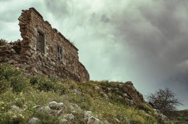 Collapsing damaged brick wall. Abandoned deserted house against cloudy sky.