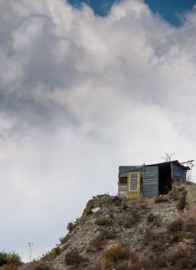 Uçurumun kenarındaki terk edilmiş depo beyaz bulutlu gökyüzüne karşı.