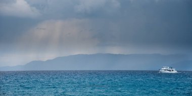 Fırtınalı bir günde okyanusta yelken açan turist motorlu teknesi. Kıbrıs 'ta Akamas Paphos