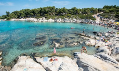 Halkidiki, Yunanistan, 26 Temmuz 2017: İnsanlar plajda yüzüyor ve dinleniyor. Kavourotripes Kayalık Kıyı, Tebeşir, Yunan