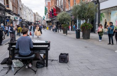 Dublin, İrlanda, 21 Temmuz 2022: Genç piyanist sokak müzisyeni Dublin, İrlanda 'da grafton sokağında piyano çalıyor ve insanlar alışveriş yapıyor