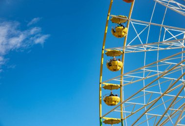 Mavi gökyüzü arka planında izole edilmiş dönme dolap lunaparkta eğleniyor.