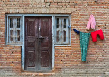 Renkli çamaşırları evin dışında kurutur. Nepal tuğla duvarı geleneksel ev.