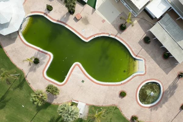 Drone aerial of abandoned deserted hotel swimming pool. Dirty water abandoned place.