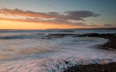 Limasol, Kıbrıs'taki Akrotiri bölgesinde kayalık bir kıyısında dramatik güzel gün batımı. Uzun pozlama fotoğraf.