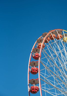 Mavi gökyüzü arka planında izole edilmiş dönme dolap lunaparkta eğleniyor.