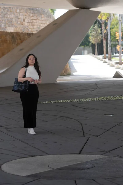 カジュアルでハンドバッグを持っている若い魅力的な女性は街の屋外で歩く服 — ストック写真