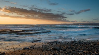 Limasol, Kıbrıs'taki Akrotiri bölgesinde kayalık bir kıyısında dramatik güzel gün batımı. Uzun pozlama fotoğraf.