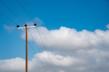 Elektrik iletim hatları dışarıya elektrik enerjisi aktarıyor. Mavi bulutlu gökyüzü. Boşluğu kopyala.