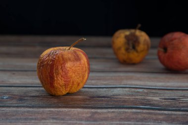 Masadaki kırmızı solmuş çürük elmalar. Çürük meyveleri enfekte eden bakteri.