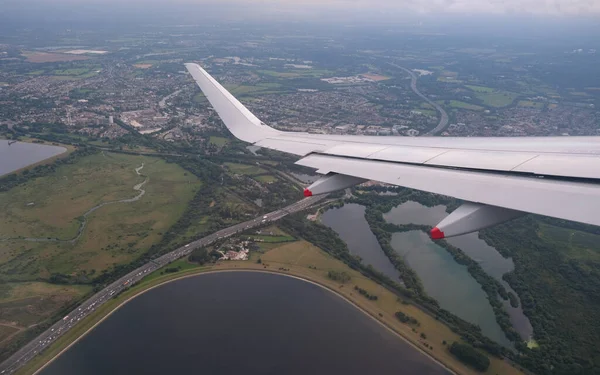ロンドン市の上空を飛行中の飛行機はイギリスを統一した 航空機の翼面窓からの空中トップビュー — ストック写真