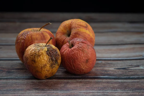 stock image Red wilted rotten apples on a table. Bacteria infected rotten fruit.