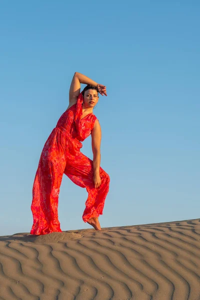 在蓝天的映衬下 年轻女子身穿红衣 在沙丘上跳舞 — 图库照片
