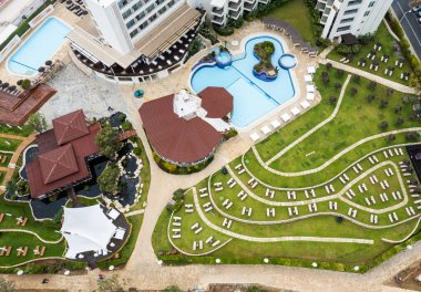 Havuzu ve plaj sandalyeleri olan lüks tatil otellerinin insansız hava aracı antenleri. Kıbrıs 'ta yaz tatilleri