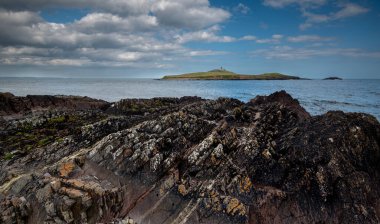 İrlanda 'daki adada deniz feneri ile birlikte göbek pamuğu kayalık kıyı şeridi..