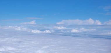 Yukarıdan bulutlu bir manzara. Mavi gökyüzü kümülüs bulutları. Yukarıdan gelen toprak.