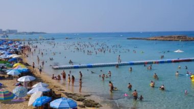Protaras, Kıbrıs, 18 Ağustos 2023: Turistlerin yüzme ve güneşlenme görüntüleri incir ağacı körfezi protaras sitesinde, yaz tatillerinde