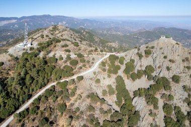 Tepenin tepesinde gözetleme kulesi istasyonu ve aktarım kulesi anteniyle dağ manzarasının insansız hava aracı antresi. Madari dağları Troodos cythe