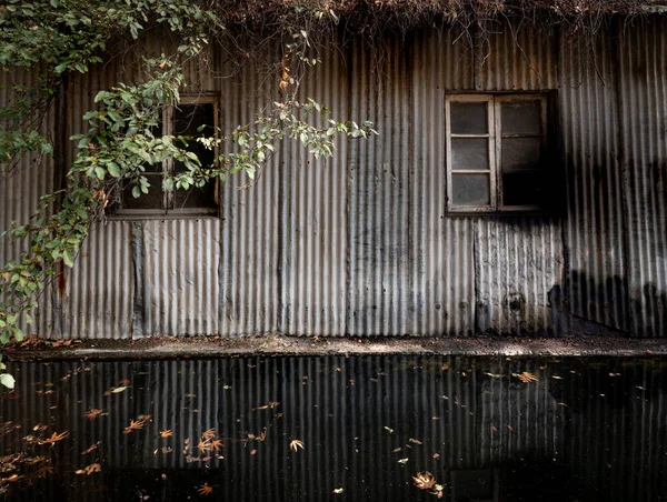 废弃的锌仓库反映在水面上 室外荒废建筑 — 图库照片