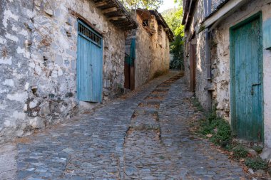 Taşlaşmış patika geleneksel bir köyden geçiyor. Tahta kapılı taş evler. Klasik mimari. Kıbrıs 'ın Palaichori köyü