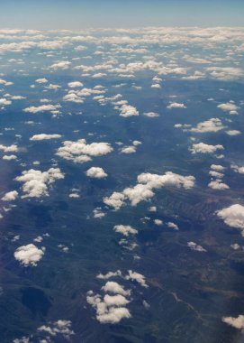 Yukarıdan bulutlu bir manzara. Mavi gökyüzü kümülüs bulutları. Yukarıdan gelen toprak.