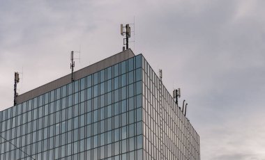 Modern ofis gökdelen binası. Çatıdaki iletişim iletim antenleri. Bulutlu gökyüzü, boşluğu kopyala.