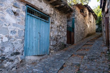 Taşlaşmış patika geleneksel bir köyden geçiyor. Tahta kapılı taş evler. Klasik mimari. Kıbrıs 'ın Palaichori köyü