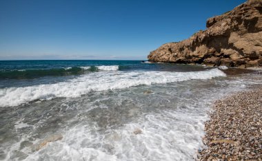 Mavi gökyüzüne karşı beyaz kayalıkların altında boş çakıl taşı tropikal plajı. Boşluğu kopyala