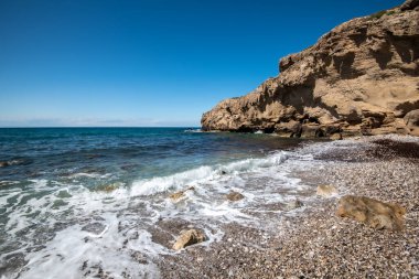 Mavi gökyüzüne karşı beyaz kayalıkların altında boş çakıl taşı tropikal plajı. Boşluğu kopyala