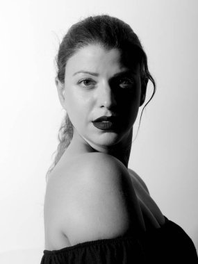 Güzel bir kızın yüksek kontrastlı siyah beyaz portresi. Beyaz arka planda kameraya bakan kadın.