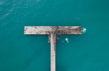 İskeleden denize dalan insanların insansız hava görüntüsü. Sağlıklı bir yaşam tarzı. İnsanlar okyanusta yüzüyor. Limni Pier Paphos