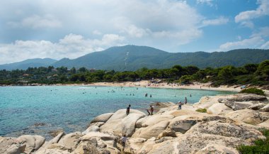 Halkidiki, Yunanistan, 27 Haziran 2017: Vourvourou plajının ünlü kayalık plajında yaşayan insanlar, Sithonia Halkidhiki Yunanistan 'da turkuaz sulara sahipler