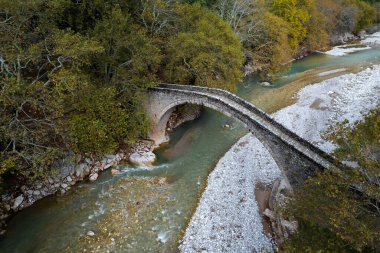 Eskiler 'in insansız hava aracı, taşlanmış, kemerli köprü St. Vissarion, sonbaharda Portaikos nehri üzerinde. Trikalla pyli köyü Teselya Yunanistan