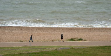 Halka açık bir sahil yolunda yürüyen tanınmamış insanlar. Aktif insanlar. Sağlıklı bir yaşam tarzı. Whitstable Birleşik Krallık