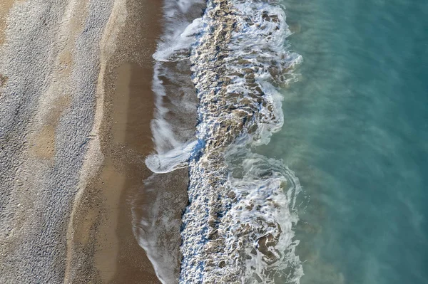 Aerial view of stormy ocean waves breaking on a sandy beach. Nature background.