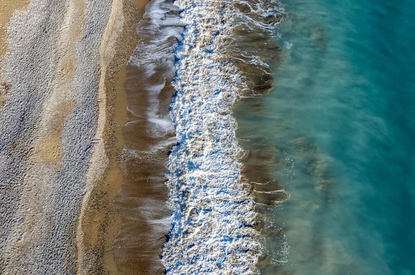 Aerial view of stormy ocean waves breaking on a sandy beach. Nature background.