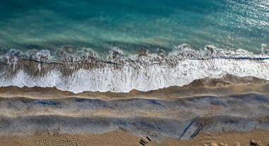 Aerial drone point of view of person walking on sand in a beach. Stormy waves idyllic beach in winter.