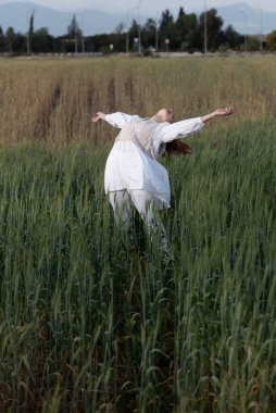 Genç dansçı kadın dışarıda dans ediyor. Çayır tarlasında modern dans gösterisi. Tasasız ve doğadaki özgürlük