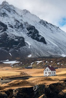 İzlanda manzarası. Arnarstapi köyündeki dağın altında küçük güzel bir ev. İzlanda, İzlanda.