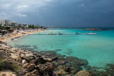 Protaras, Kıbrıs, 12 Mayıs 2024: İnsanlar fırtınalı bir günde Protaras turizm beldesi Kıbrıs 'taki ünlü İncir ağacı koyunda dinleniyor ve yüzüyorlar. Yaz tatili