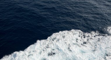 Derin mavi okyanus suyu çalkalanıyor beyaz bir kayığın geçtiği yerde