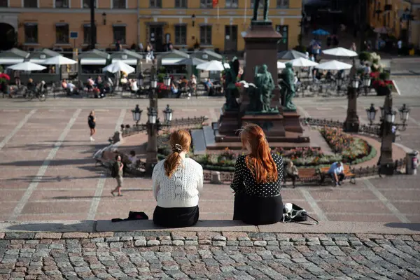 stock image Two young women are relaxing on a sunny day in a plaza in senate square helsinki, finland.