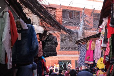 Katmandu, Nepal, 8 Mart 2020: Yoğun bir pazarda gezen turistler, giysileri asılmış ve elektrik kablolarında thamel, kathmandu, nepal.